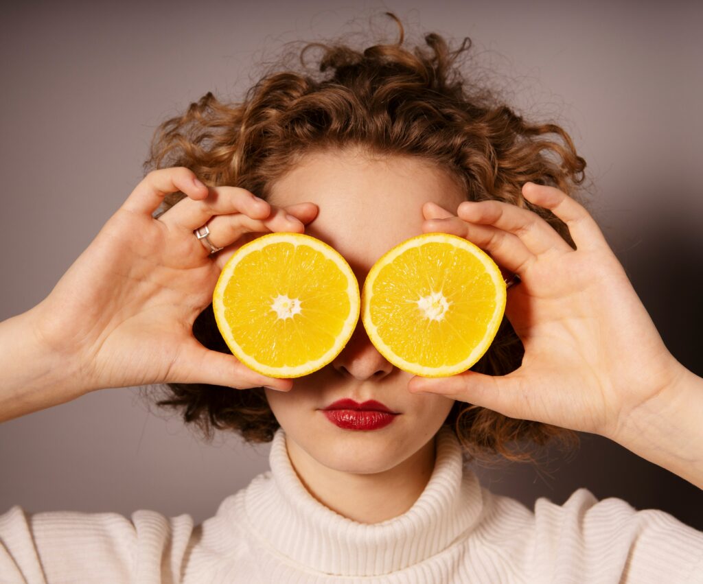 Two oranges in hands of a woman who covers her eyes with