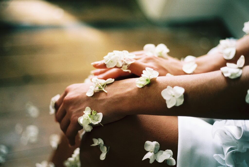 Arms and legs of a woman in white dress covered with white flowers