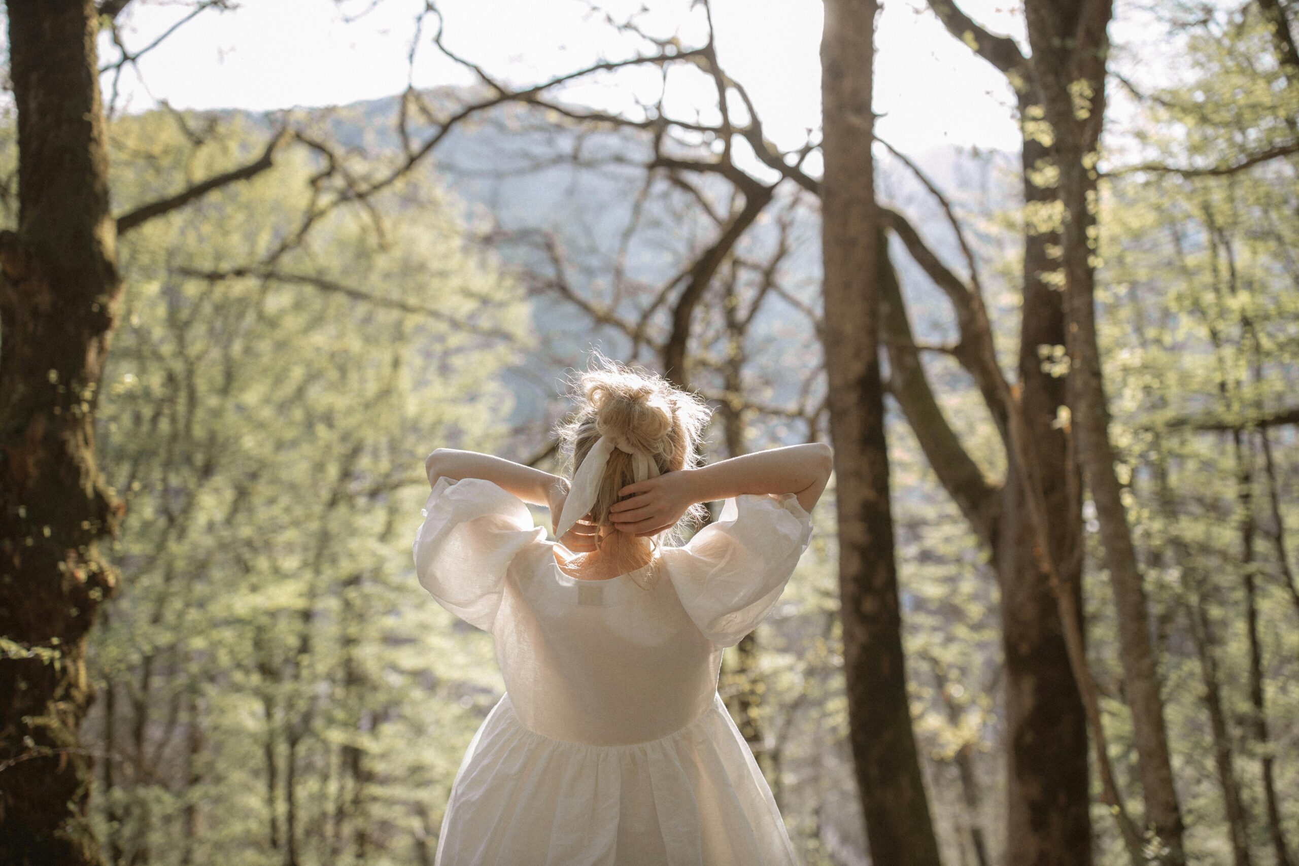 Woman in white dress practicing forest bathing