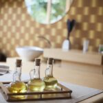 Glass bottles of body massage oil on a spa treatment bed in a wellness room.