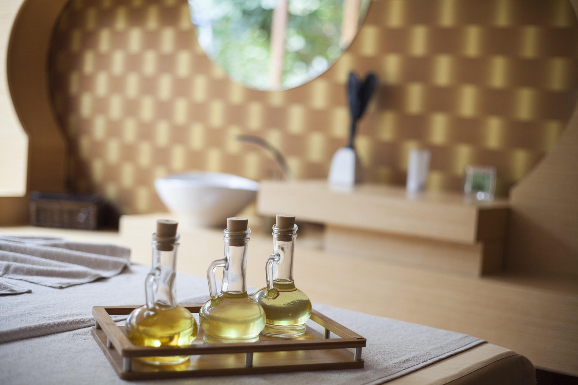 Glass bottles of body massage oil on a spa treatment bed in a wellness room.