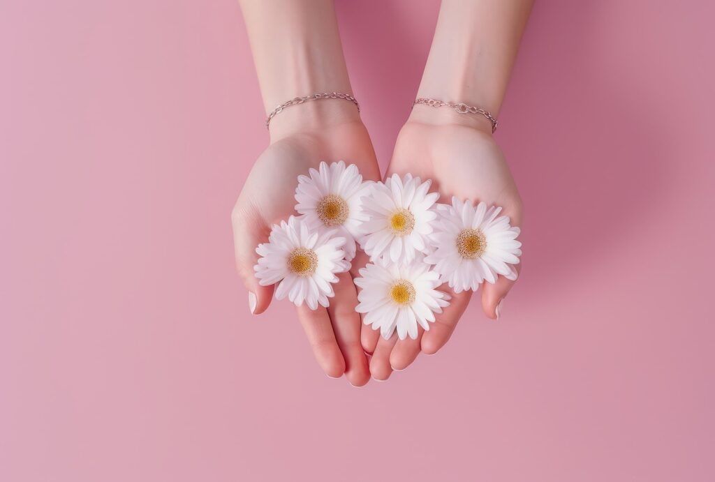 Two hands holding white flowers in pink background