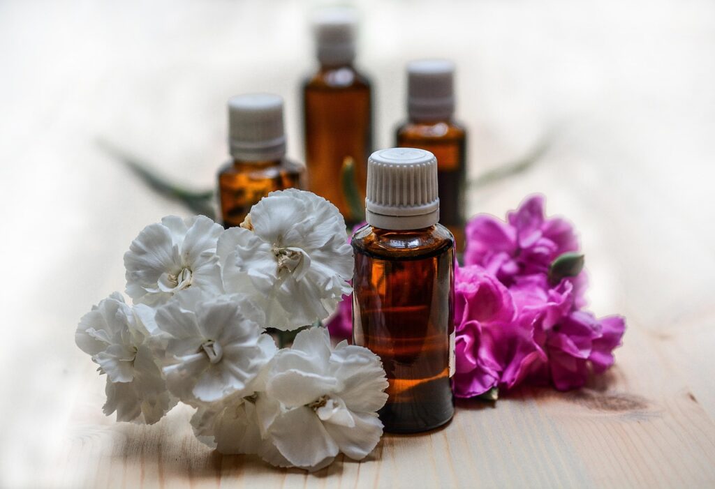 Four botles of essential oils and pink and white flowers around