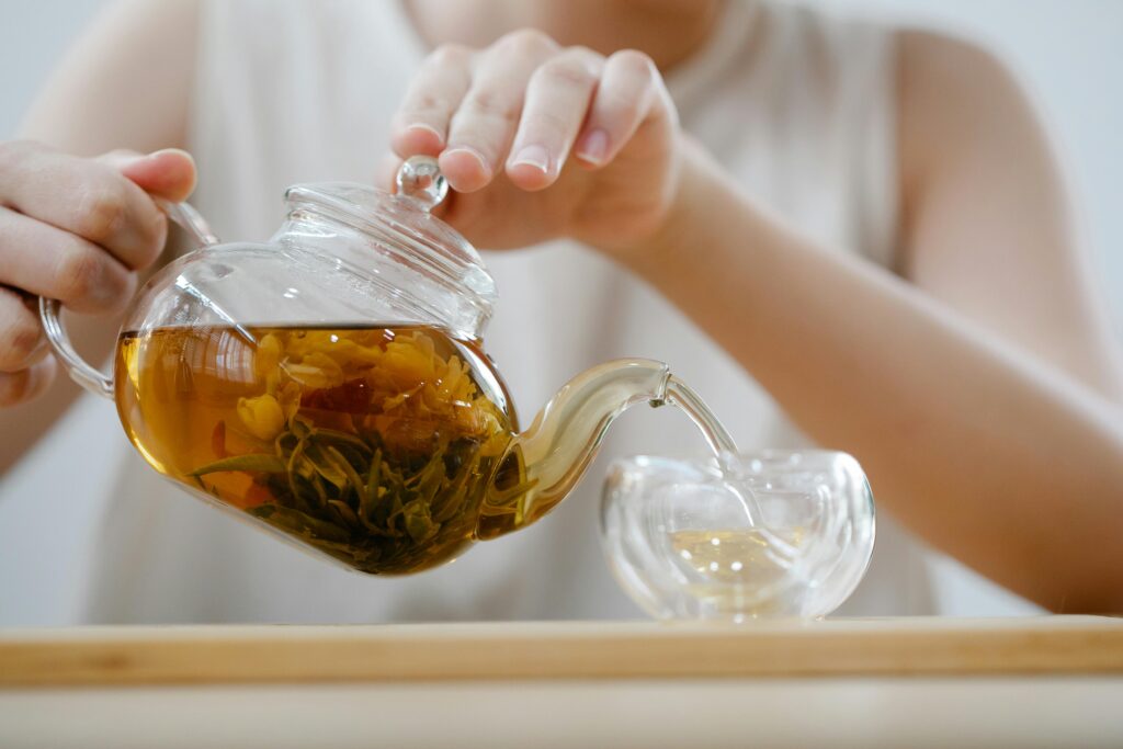 Lady with tea pot on her hands, poring tea in a cup, tea ritual from natural plants
