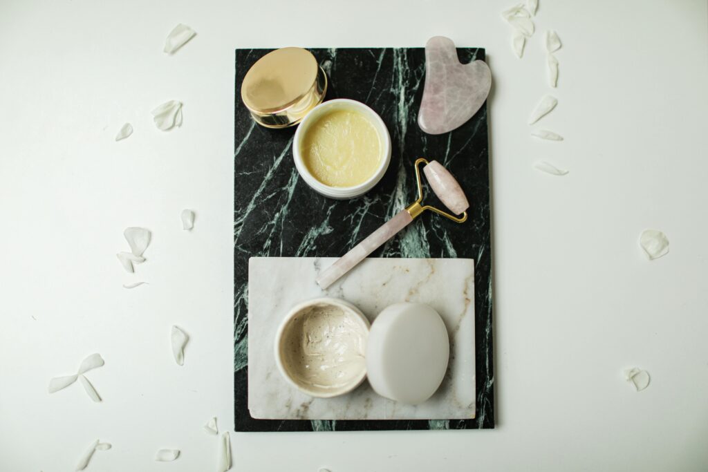 Gua sha roller jade and two facre cream treatments on a black and white board