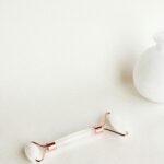 Gua sha on a clean surface and a white decoration vase