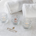 Massage setup with three candels and two white towels with Essential-Moments logo on.