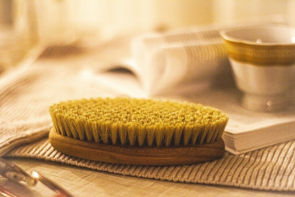 Morning routine including body brush for lymphatic drainage and background with pages of a book and a cup