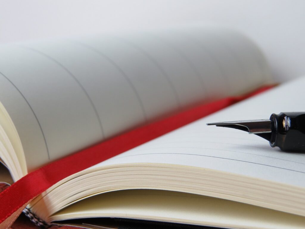 White Journal with red sign and a pen 