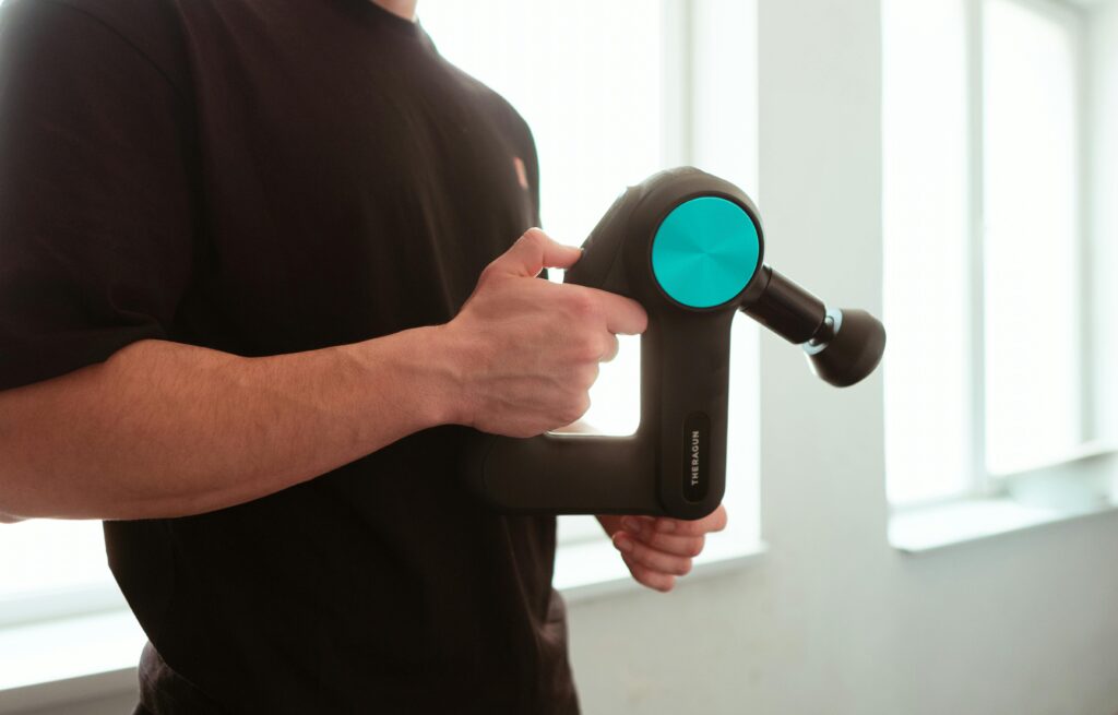 Massage Gun held by man with black shirt applying pressure on muscle