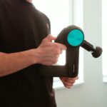 Massage Gun held by man with black shirt applying pressure on muscle