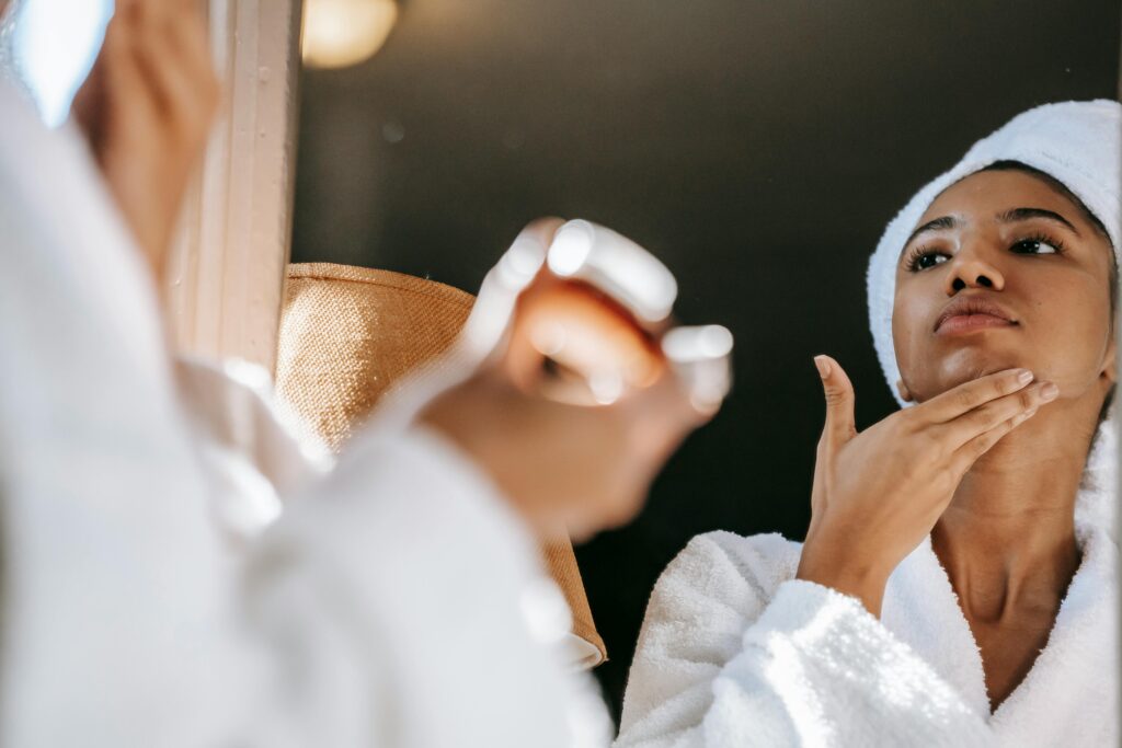 Lady applying cream on face, skin care routine in front of a mirror