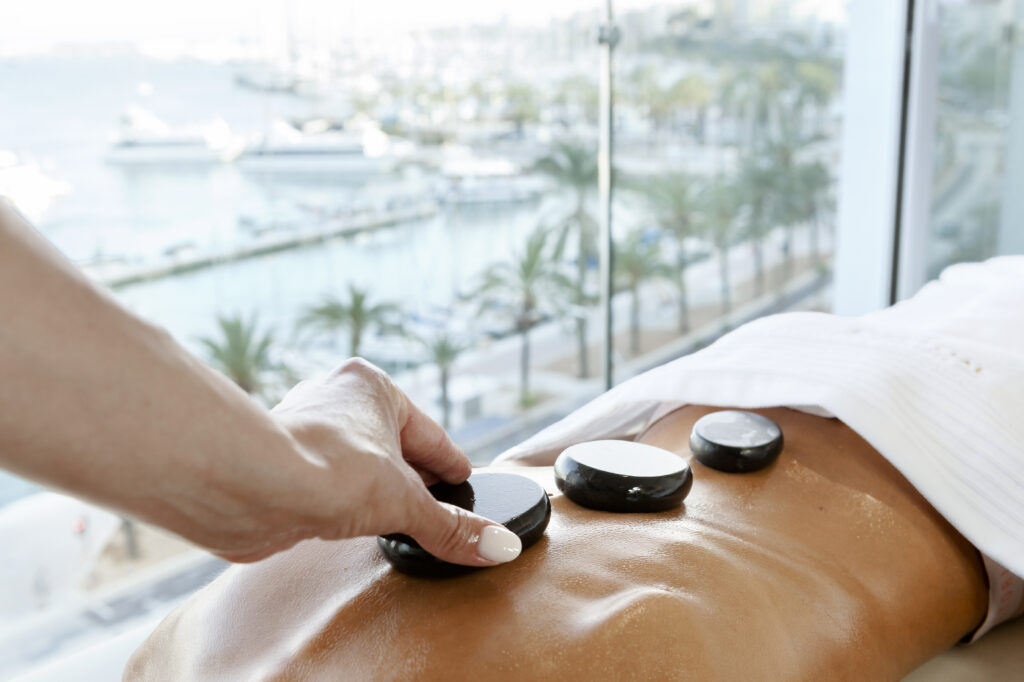 Hot stone massage performed by Essential Moments , hand on the stones