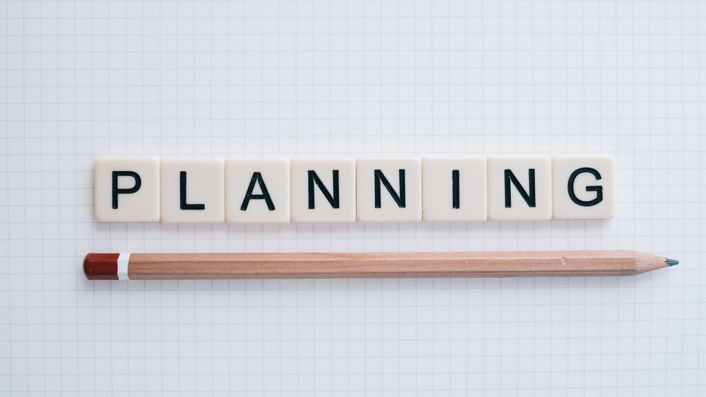Letters and a pencil on a sheet of paper with the message PLANNING