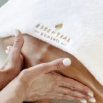 Neck, shoulders and back massage by Essential Moments on client covered by a white towel with essential moments logo omn
