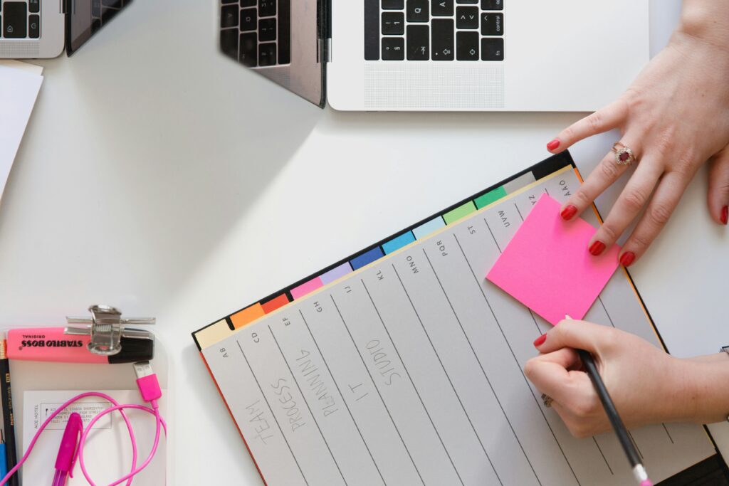 Schedule for massage business, agenda and laptop with pink paper and hand holding pen
