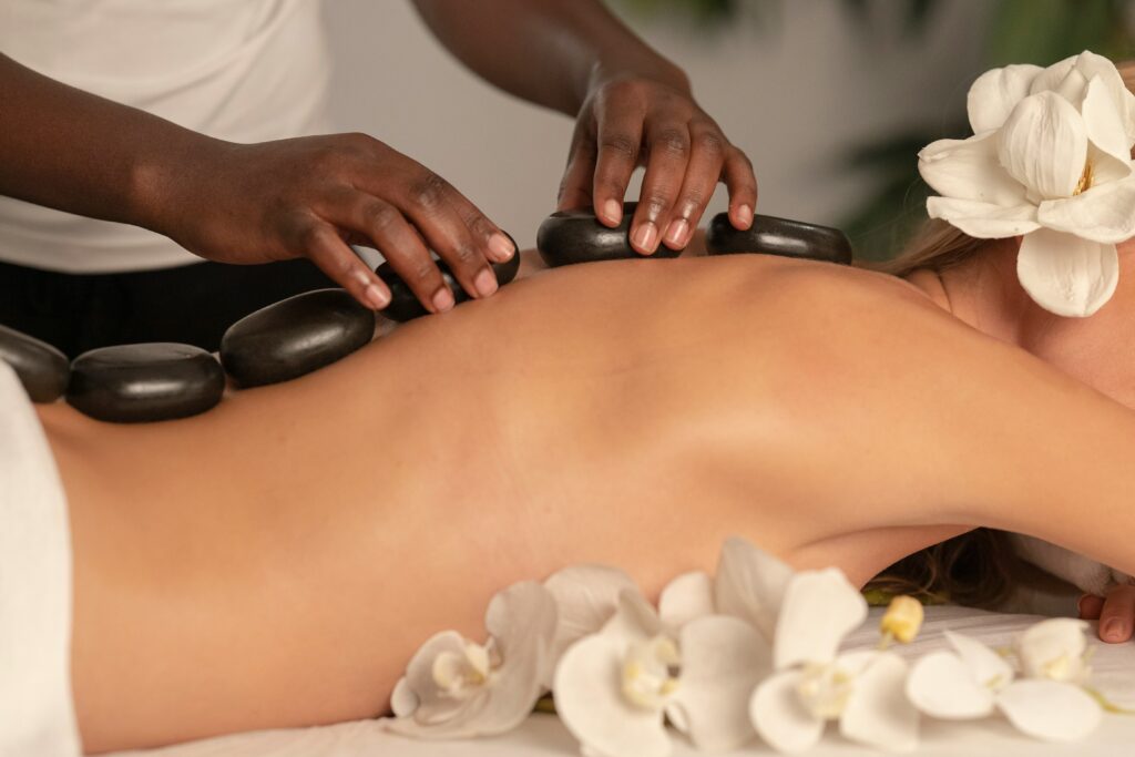 Premium massage experience, client receiving a massage and white flowers near therapist hands