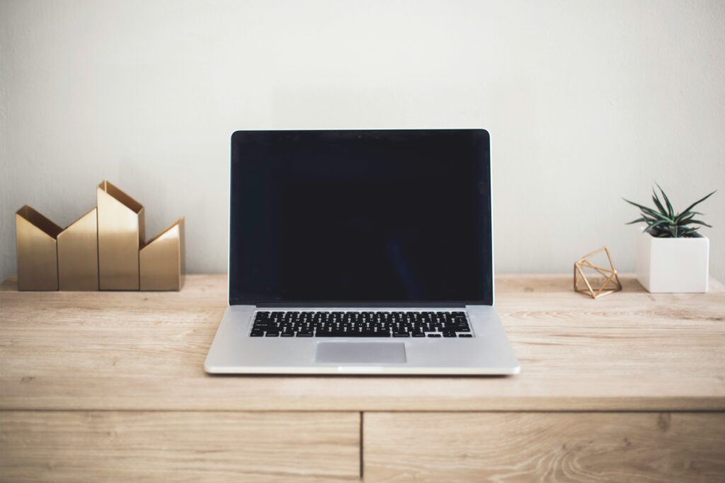 Booking Appfor massage business , Computer on a wood table, office tools and a plant near