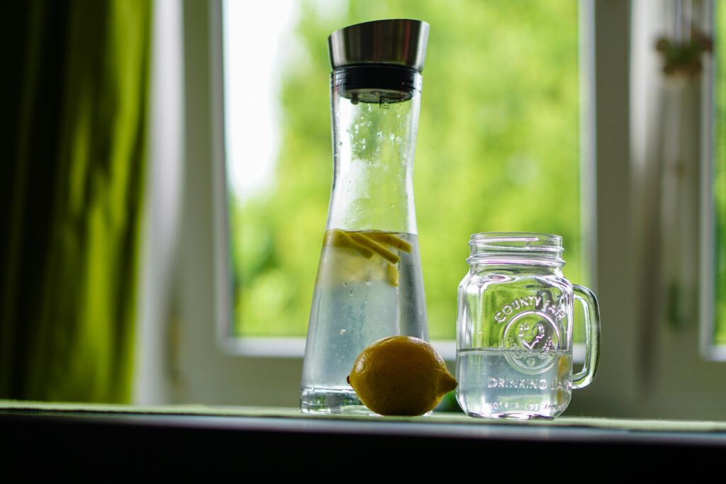 summer hydration rituals, water bottle and lemon on a window